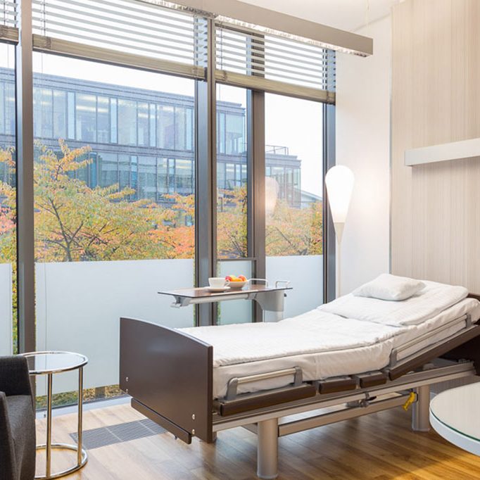 Modernes Patientenzimmer mit einem Bett und groĂźem Fenster