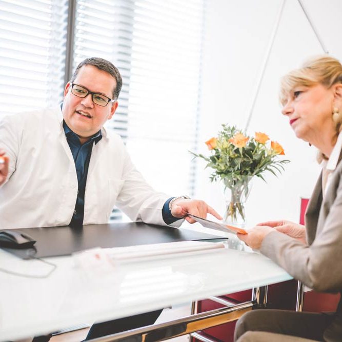 Stefan Mühlbauer sitzt mit Patient an Tisch