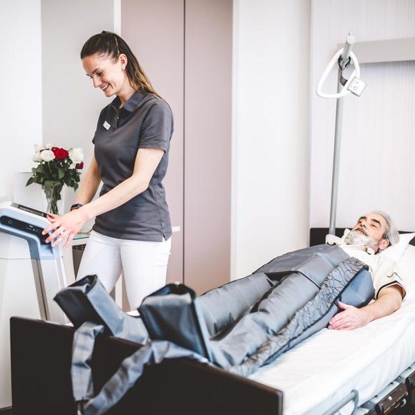 Patient wird von Physiotherapeut im Bett behandelt