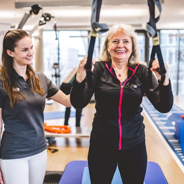 Patient trainiert an Seilen mit Physiotherapeutin