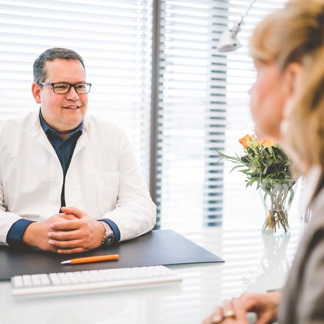 Stefan Mühlbauer im Patientengespräch am Tisch
