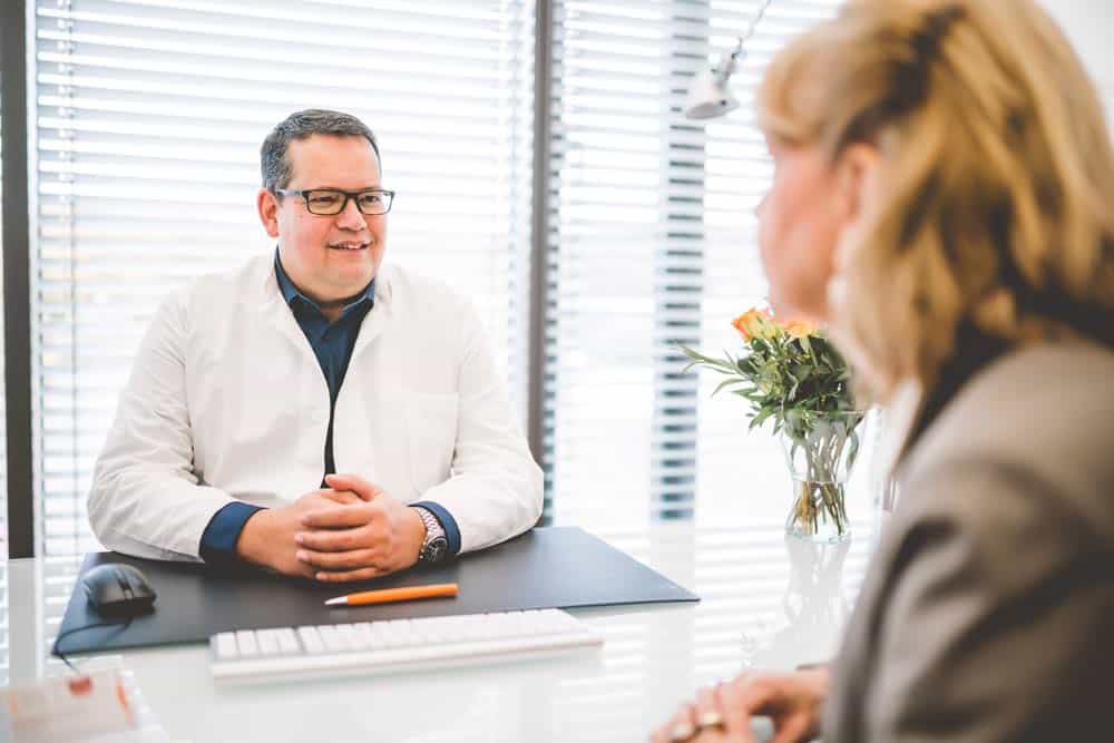 Stefan Mühlbauer im Patientengespräch am Tisch