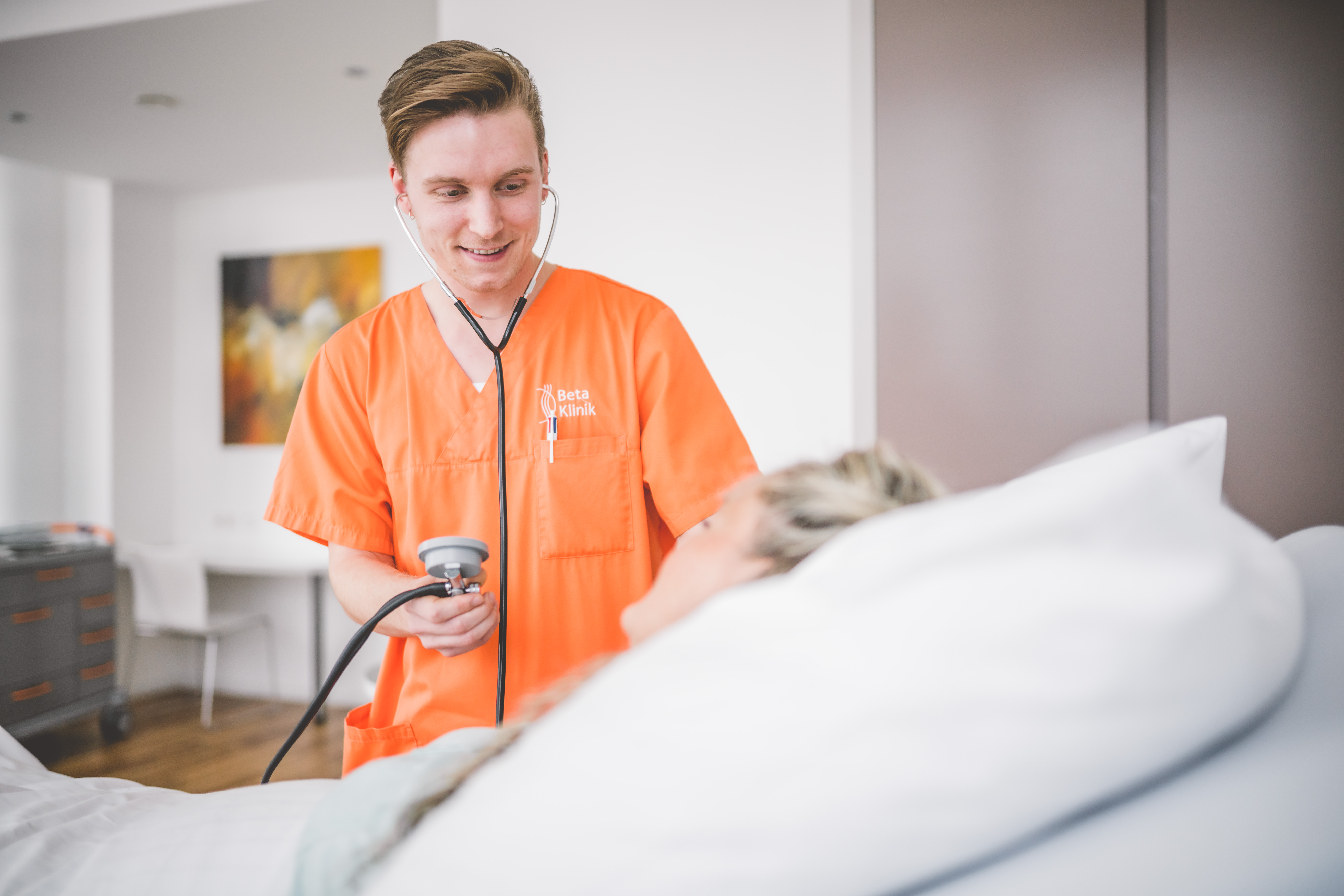 Medizinischer Fachangestellter misst den Blutdruck bei einer Patientin im Stationsbett.