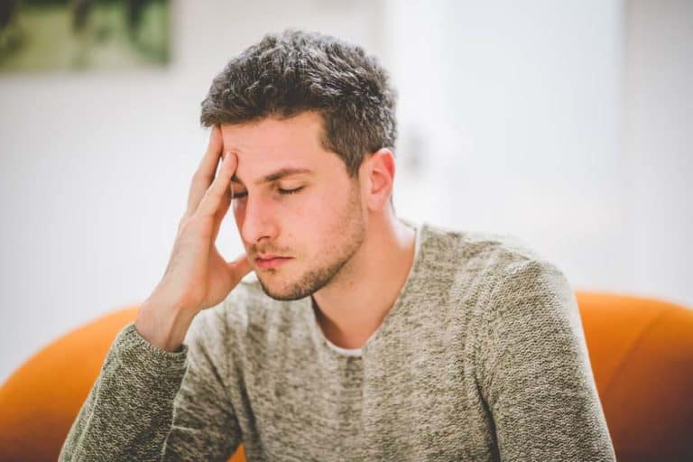 Mann mit Kopfschmerzen fasst sich an die Schläfe