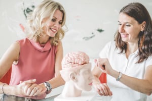 Patientengespräch Ärztin zeigt Patientin Modell eines Gehirns