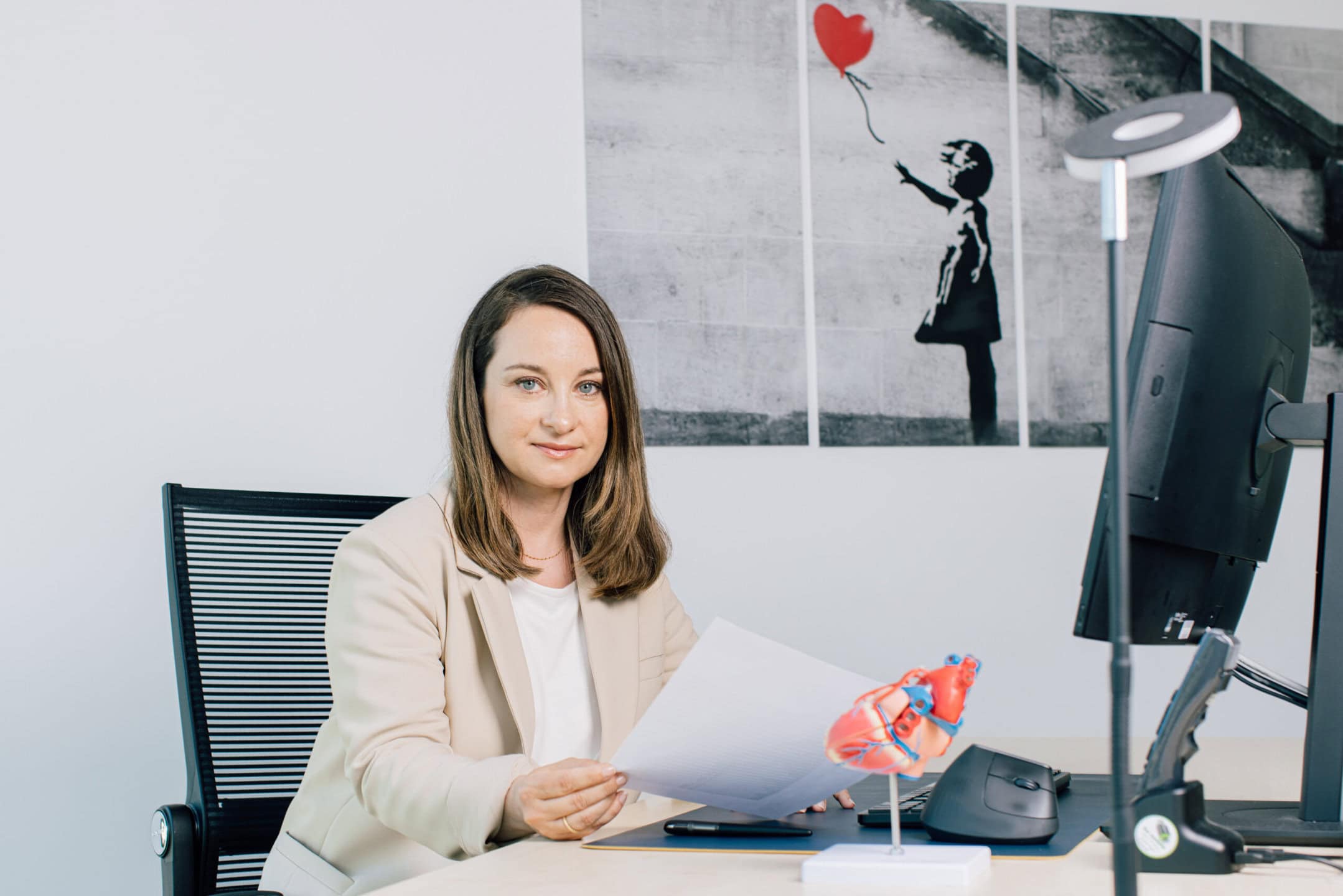 Kardiologin mit Herzmodell am Computer.