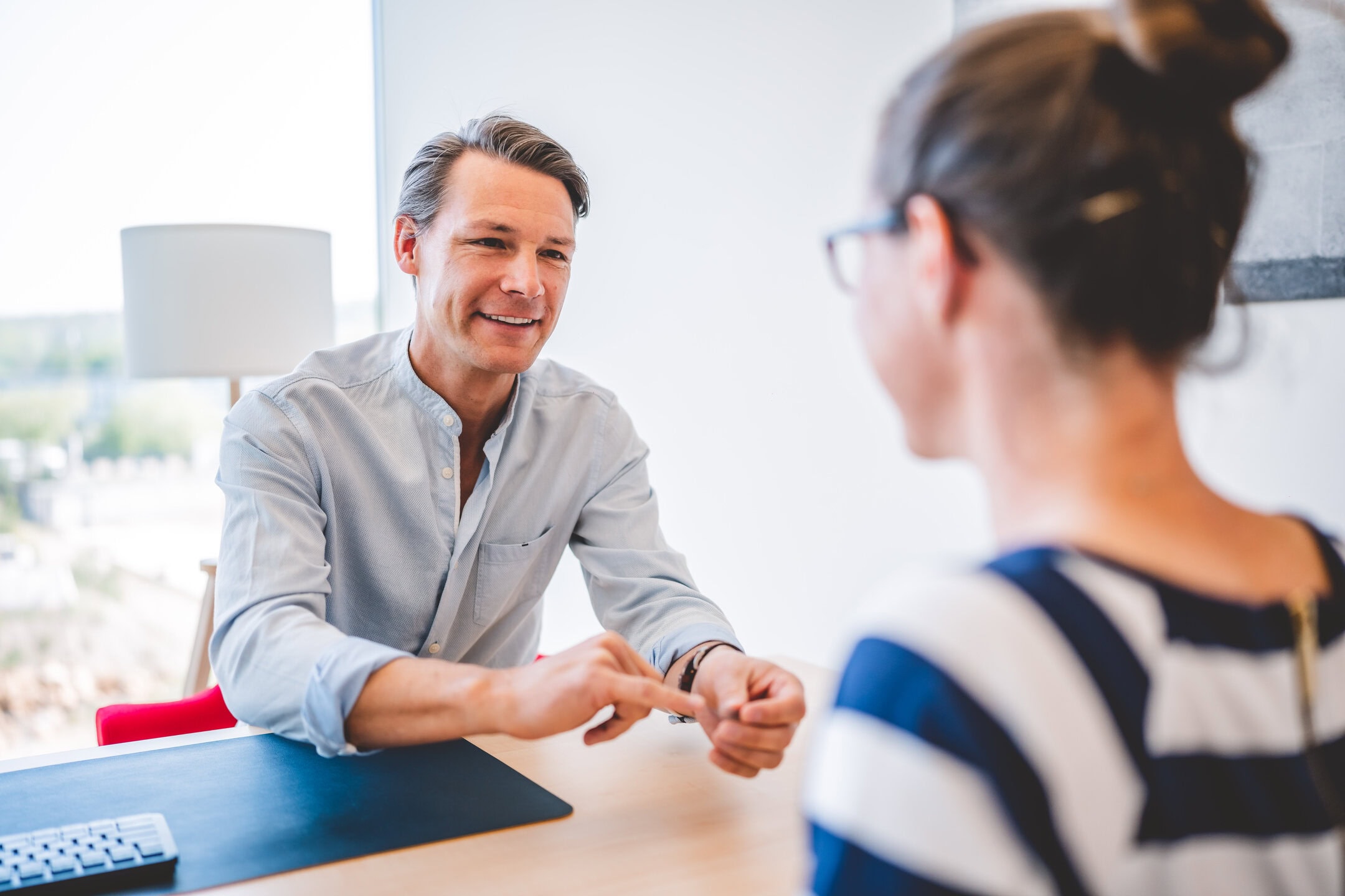 Ein Mann und eine Frau unterhalten sich an einem Tisch in einem hellen Büro.