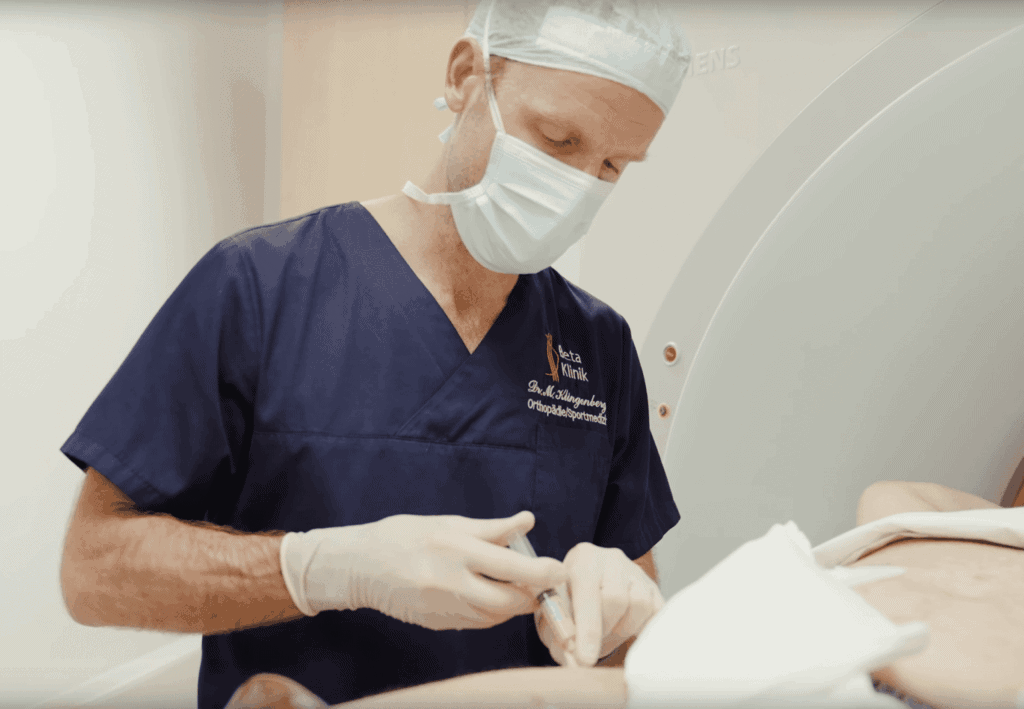 Ein Arzt in blauer OP-Kleidung führt ein medizinisches Verfahren an einem Patienten durch.