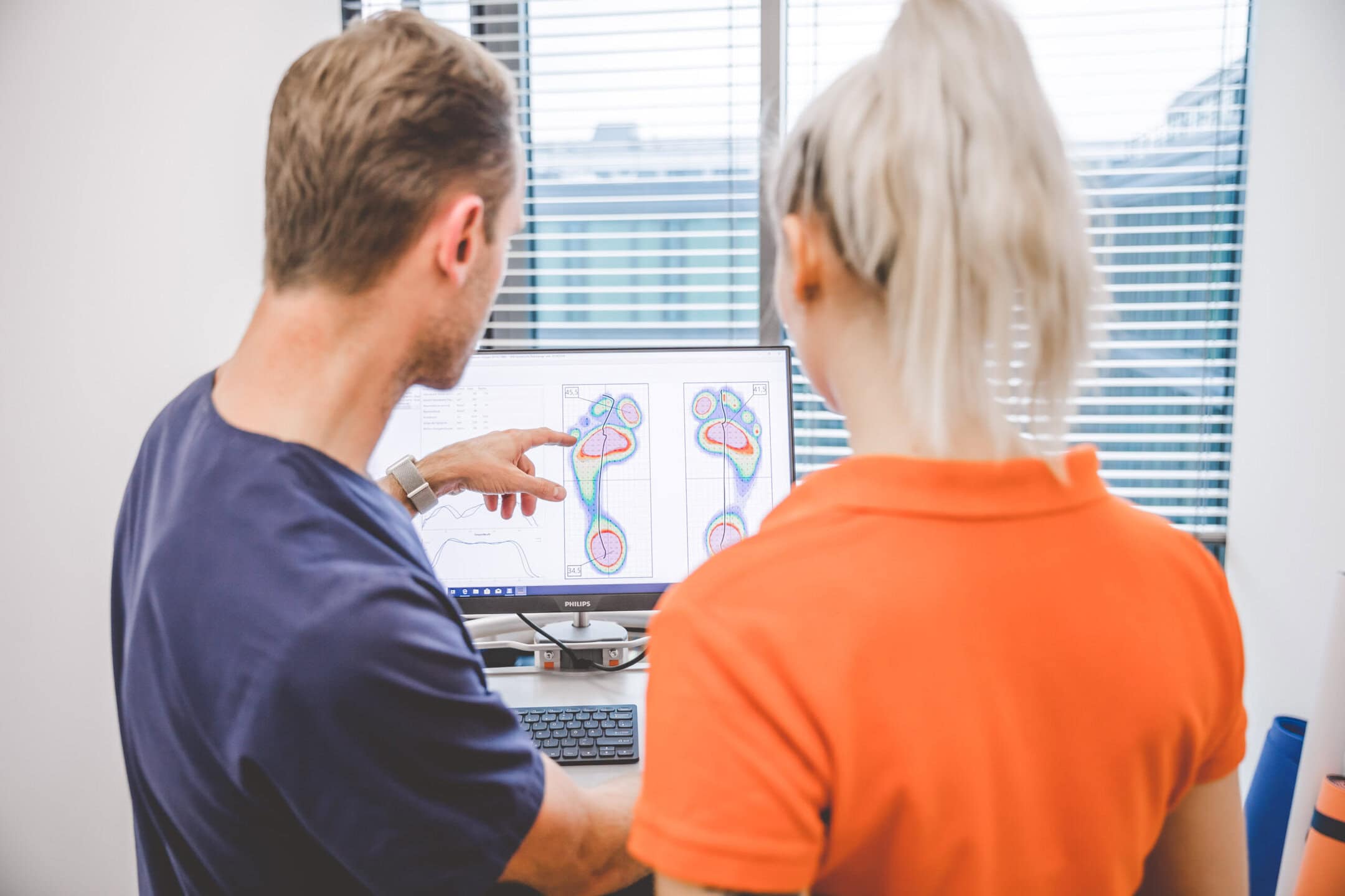 Ein Mann und eine Frau betrachten Fußabdruck-Analysen auf einem Computerbildschirm.