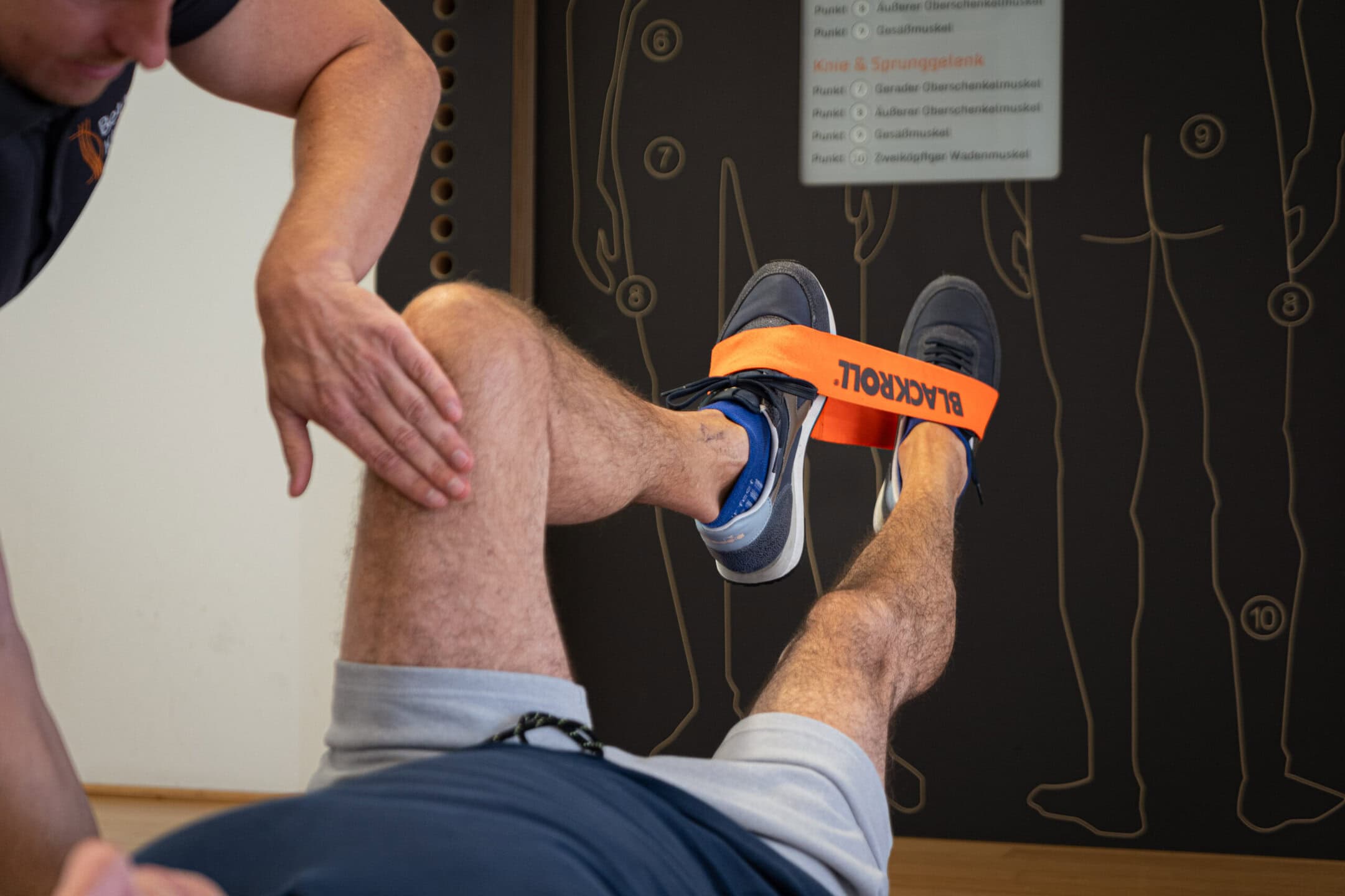 Patient trainiert mit Physiotherapeut seine Gelenke mit Hilfe eines Fitnessbands