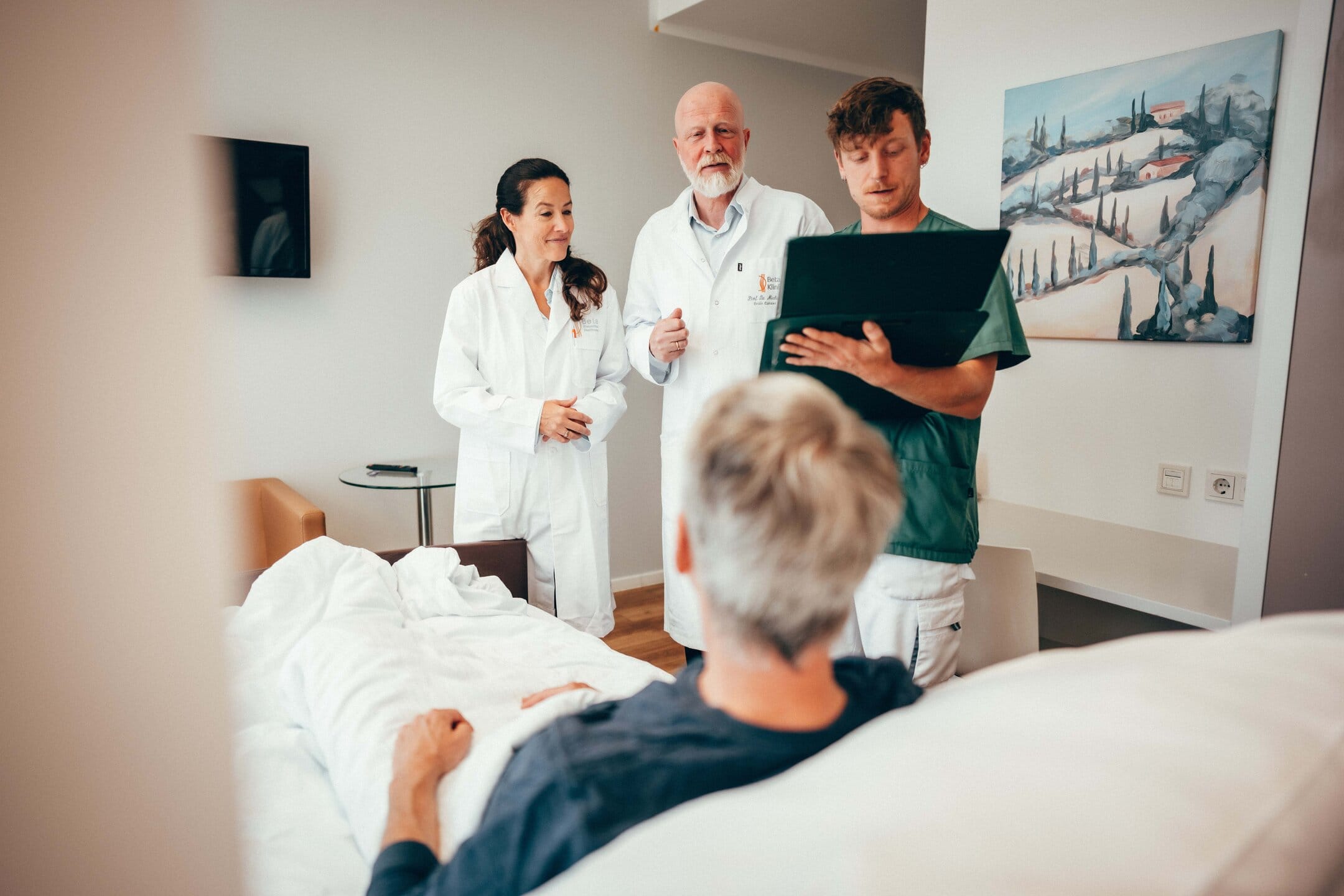 Neuroonkologen Dr. Sabel und Dr. Rapp sprechen mit Patienten im Patientenzimmer