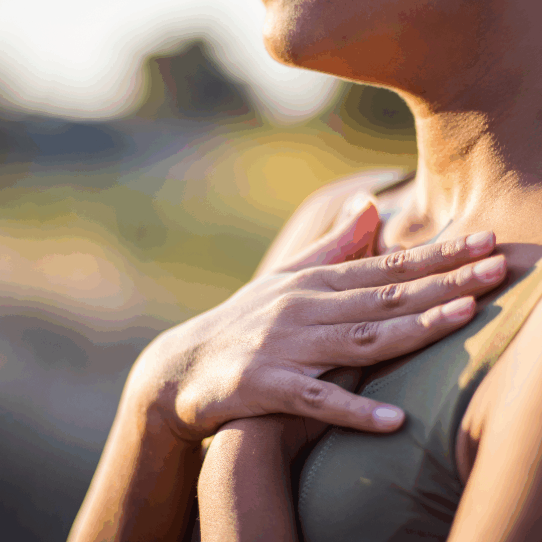 Eine junge Frau hält ihre Hände auf ihre Brust und atmet ein.