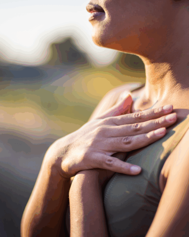 Eine junge Frau hält ihre Hände auf ihre Brust und atmet ein.